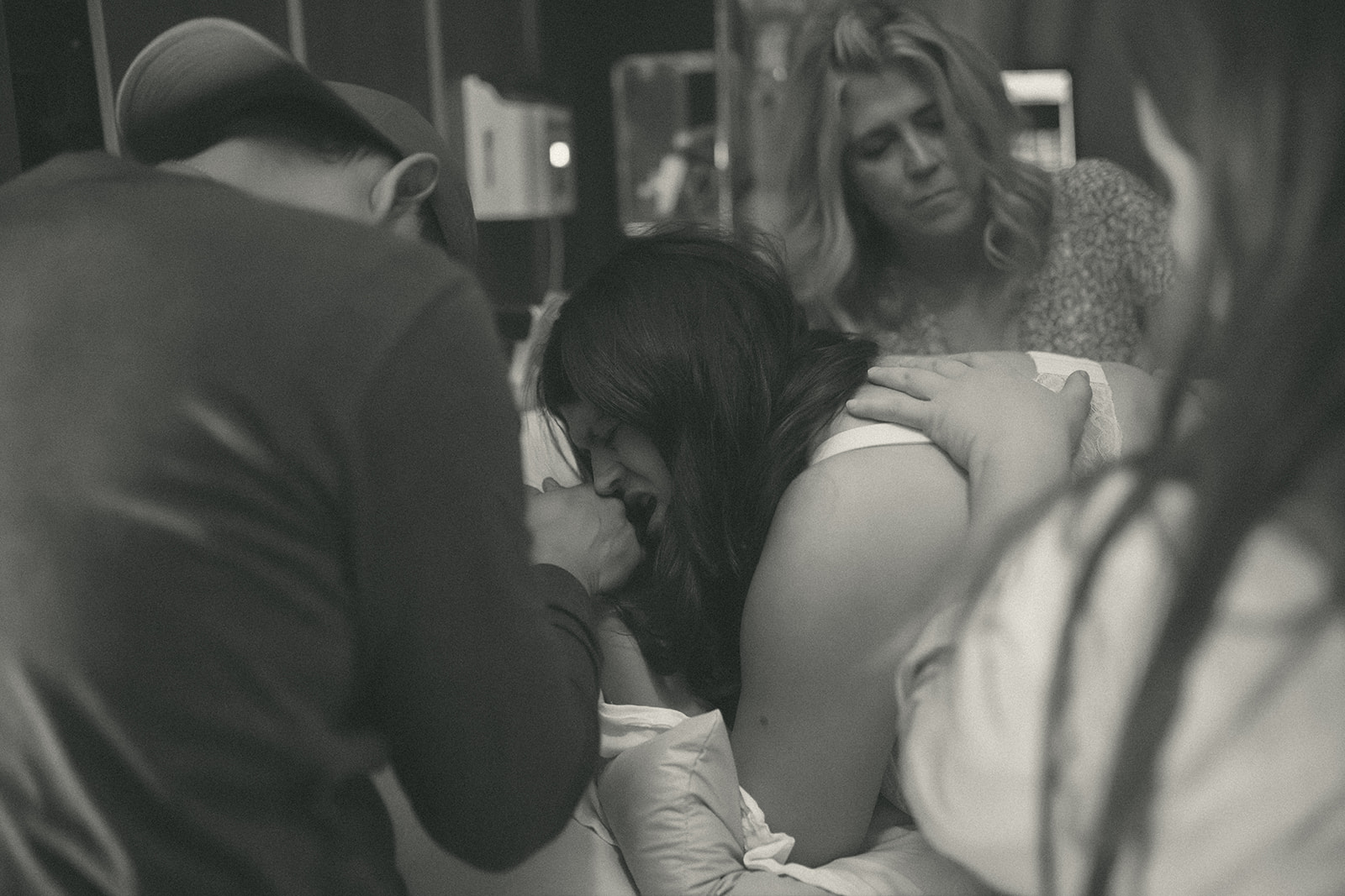 A mother to be screams while in labor at one of the birthing centers in Kalispell, MT while holding hands with her husband and supported by doulas and midwives
