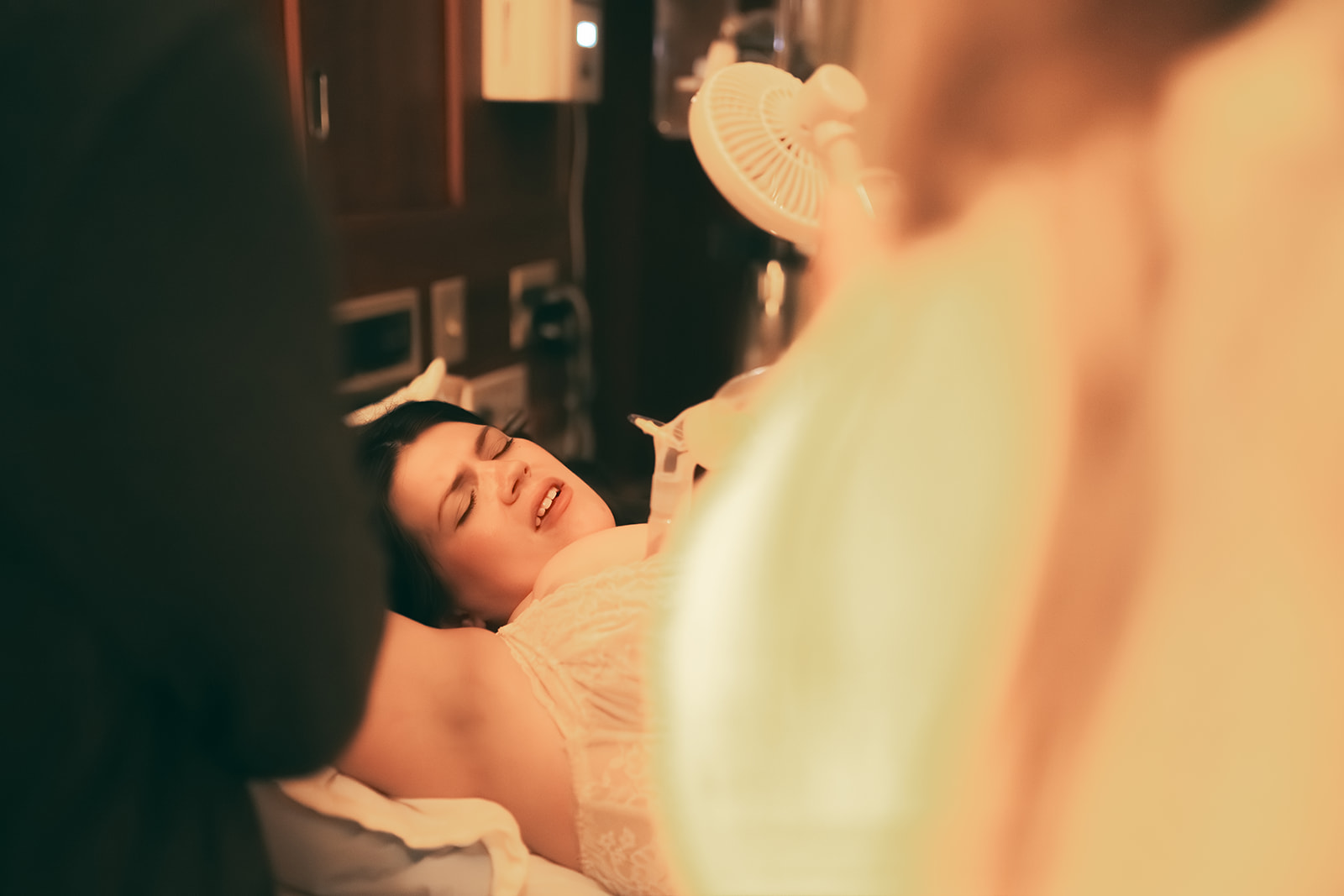 A look at a mother in labor in a hospital bed between the shoulders of two doulas in Kalispell, MT