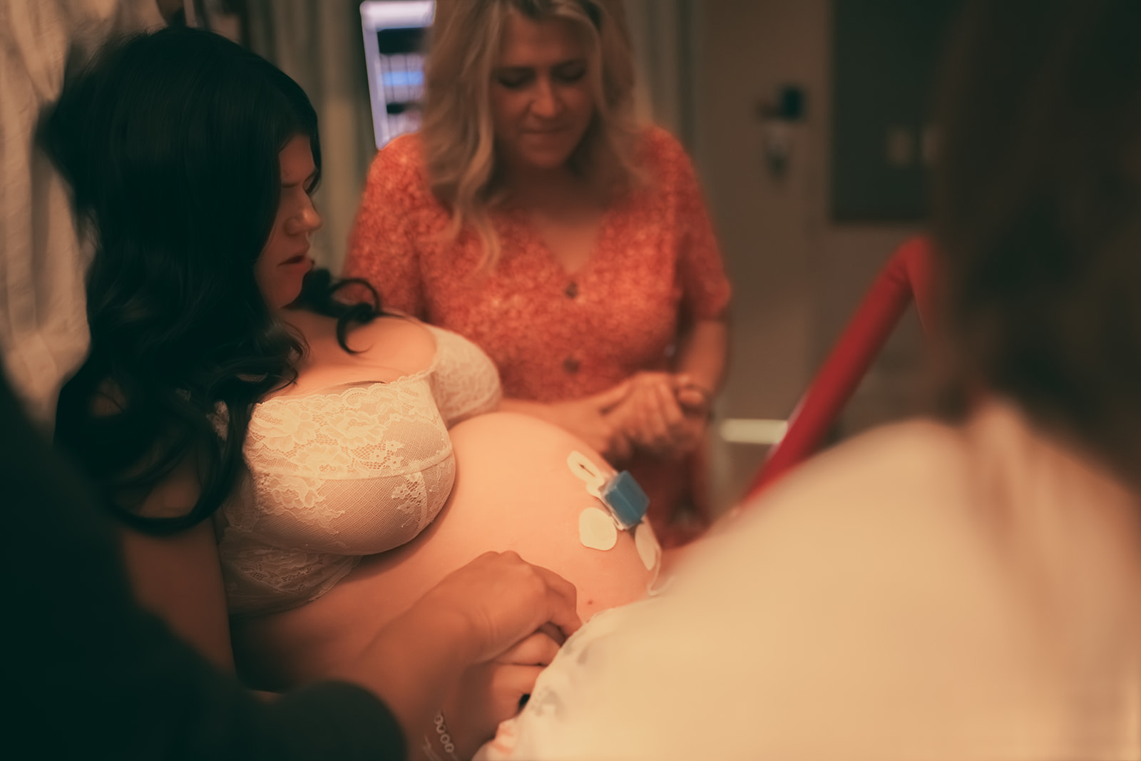 A pregnant woman on the hospital bed during labor holding mom and husband's hands