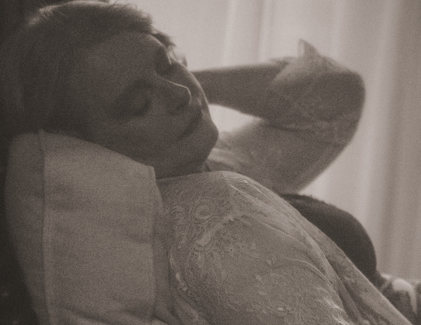 A woman leans back on a couch in a white lace blouse