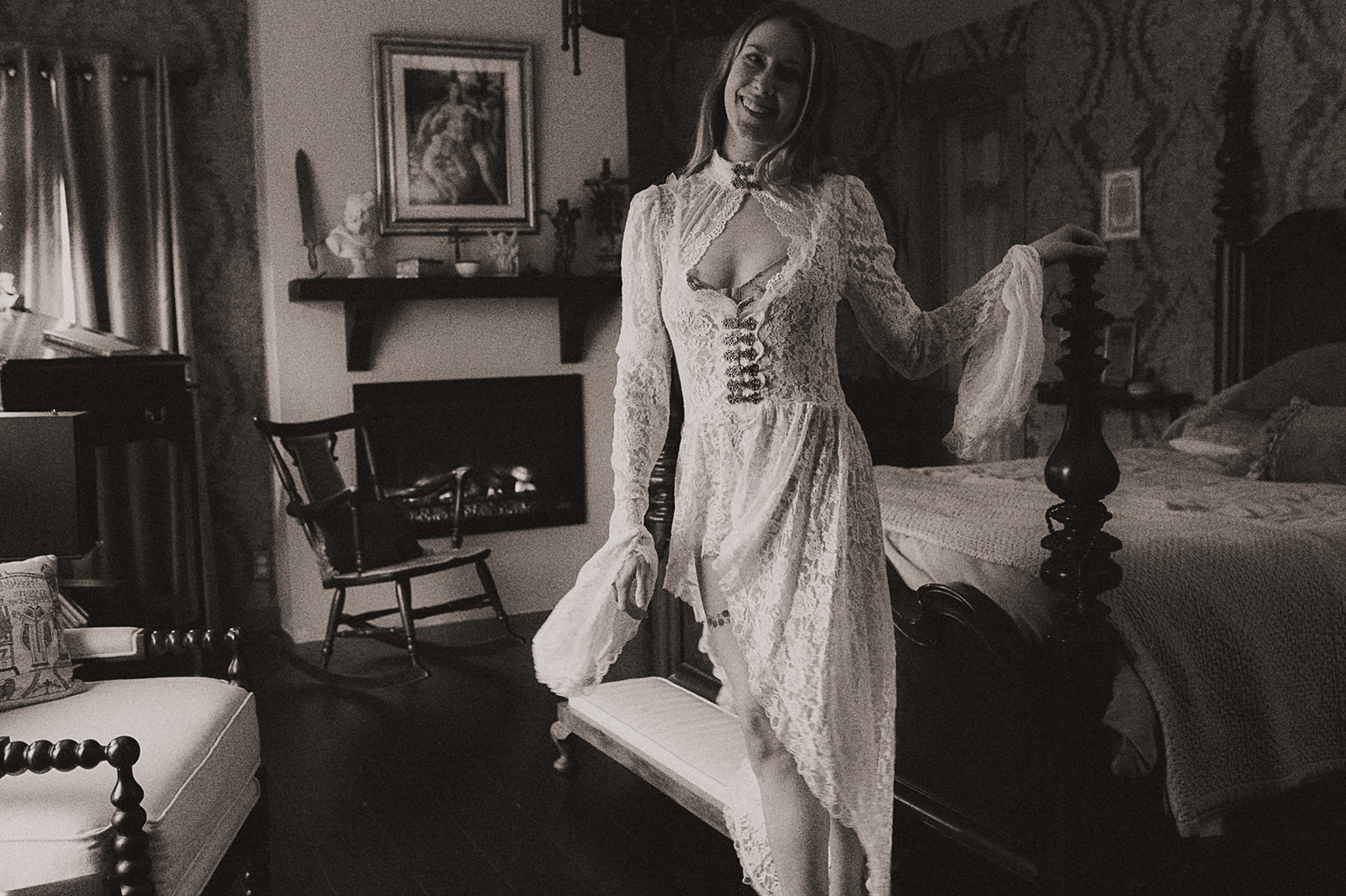 A woman hangs on the bed post in white lace lingerie