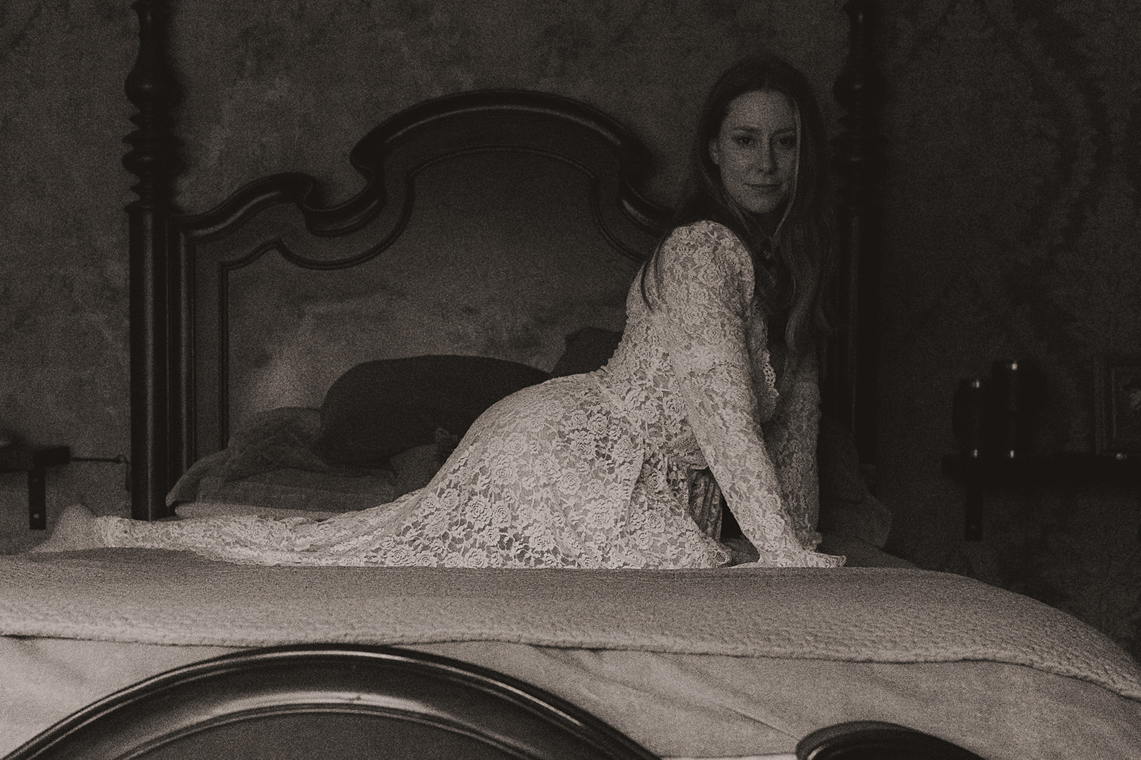 A woman leans across a bed in a white lace gown after visiting beauty salons in Missoula, MT