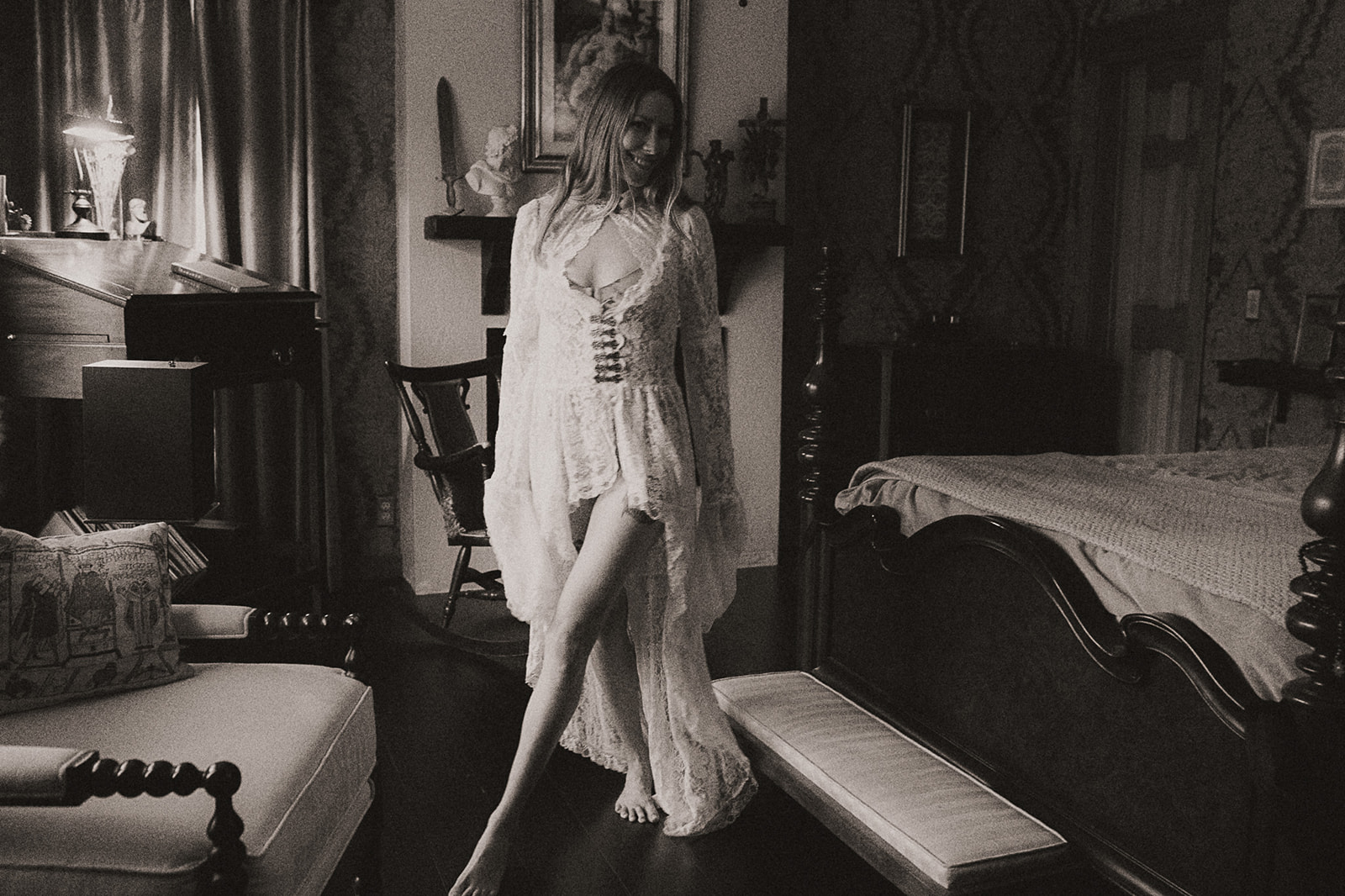 A woman in white lace lingerie and gown walks in a luxurious bedroom smiling after visiting beauty salons in Missoula, MT