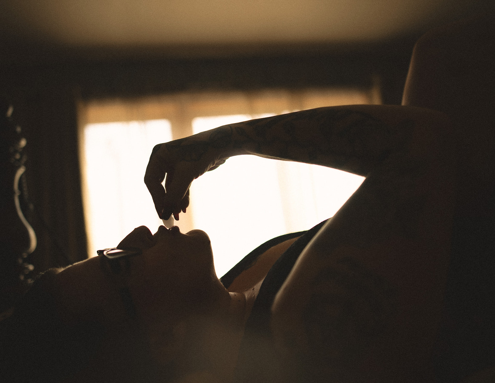 A woman lays on a bed touching ice to her lips after finding black lace Bozeman lingerie