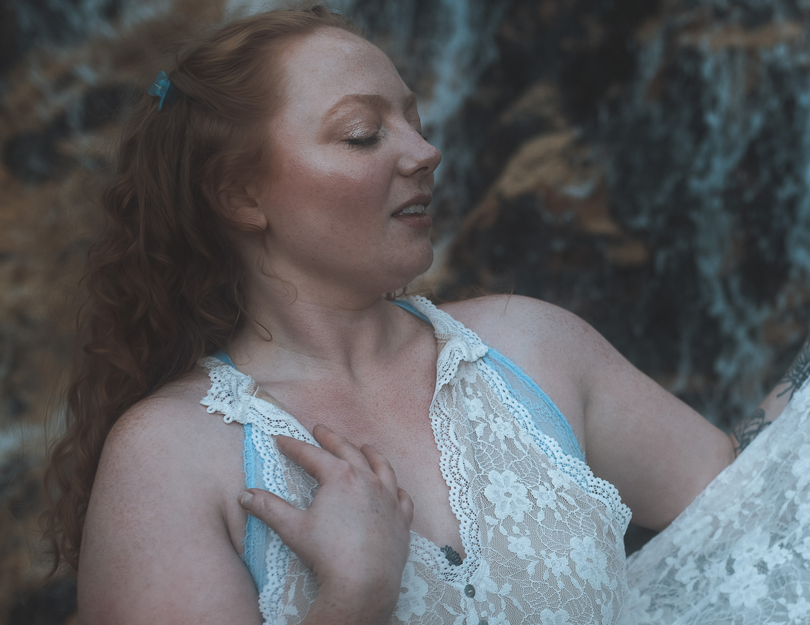 A red hair woman wearing white lace lingerie rests a hand on her chest after visiting bridal shops in Kalispell, MT