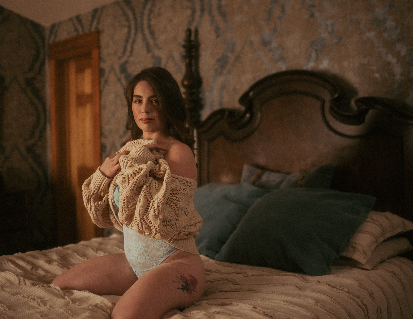 A woman removes her knit sweater to reveal lace lingerie while kneeling on a bed after visiting bridal shops in Missoula