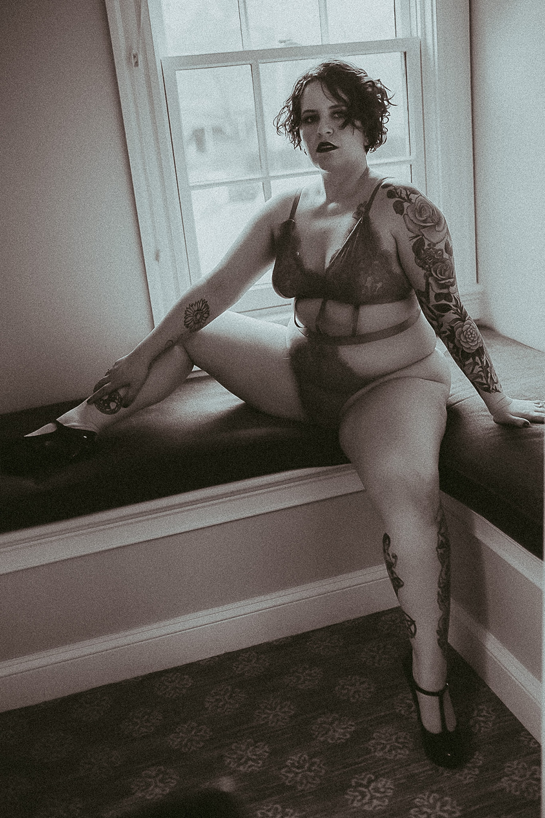 A woman sits with legs open on a bench in a window in lingerie after getting Missoula laser hair removal
