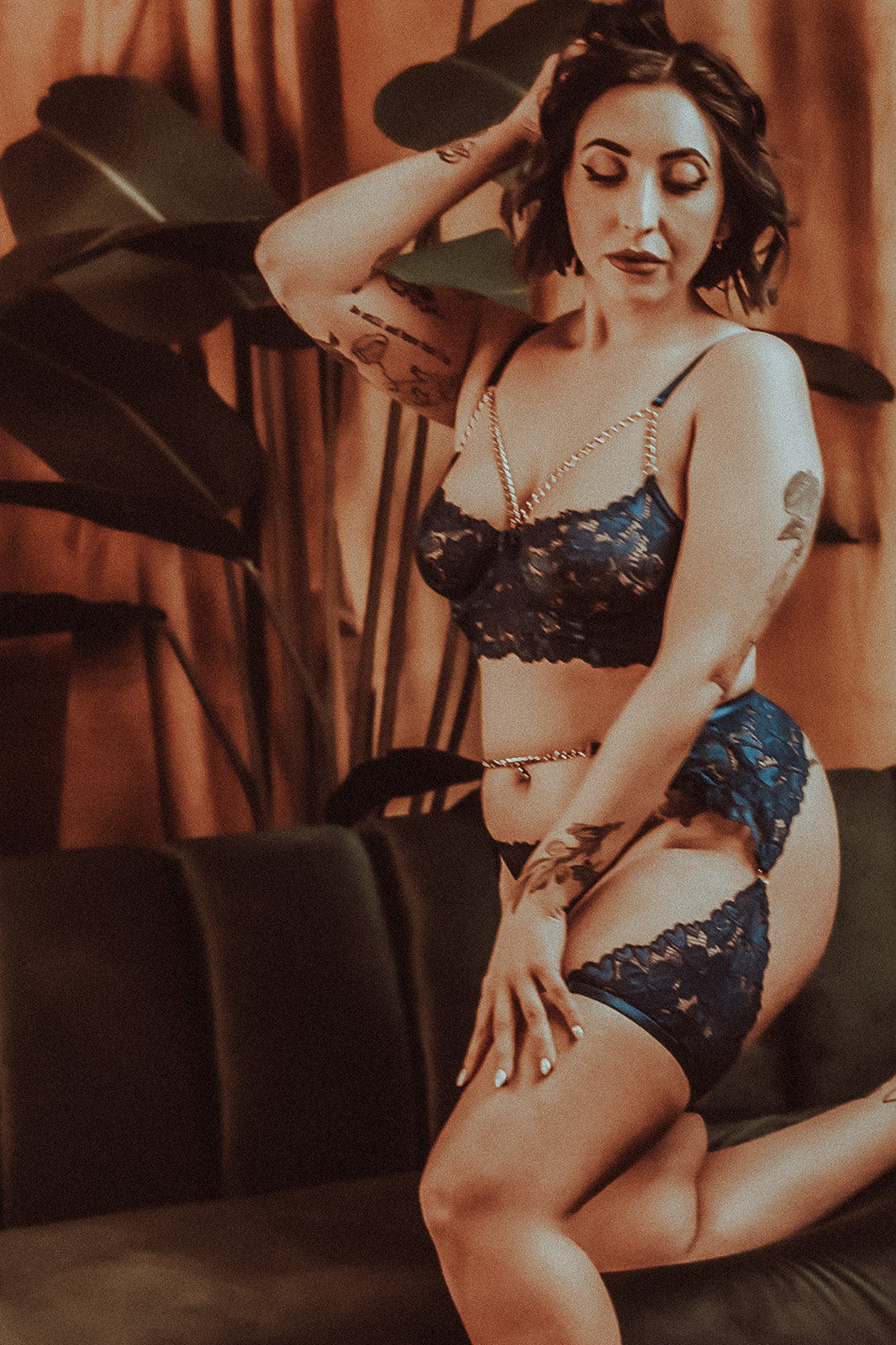 A woman in black lace lingerie kneels on a couch after vistiing Missoula Lingerie stores