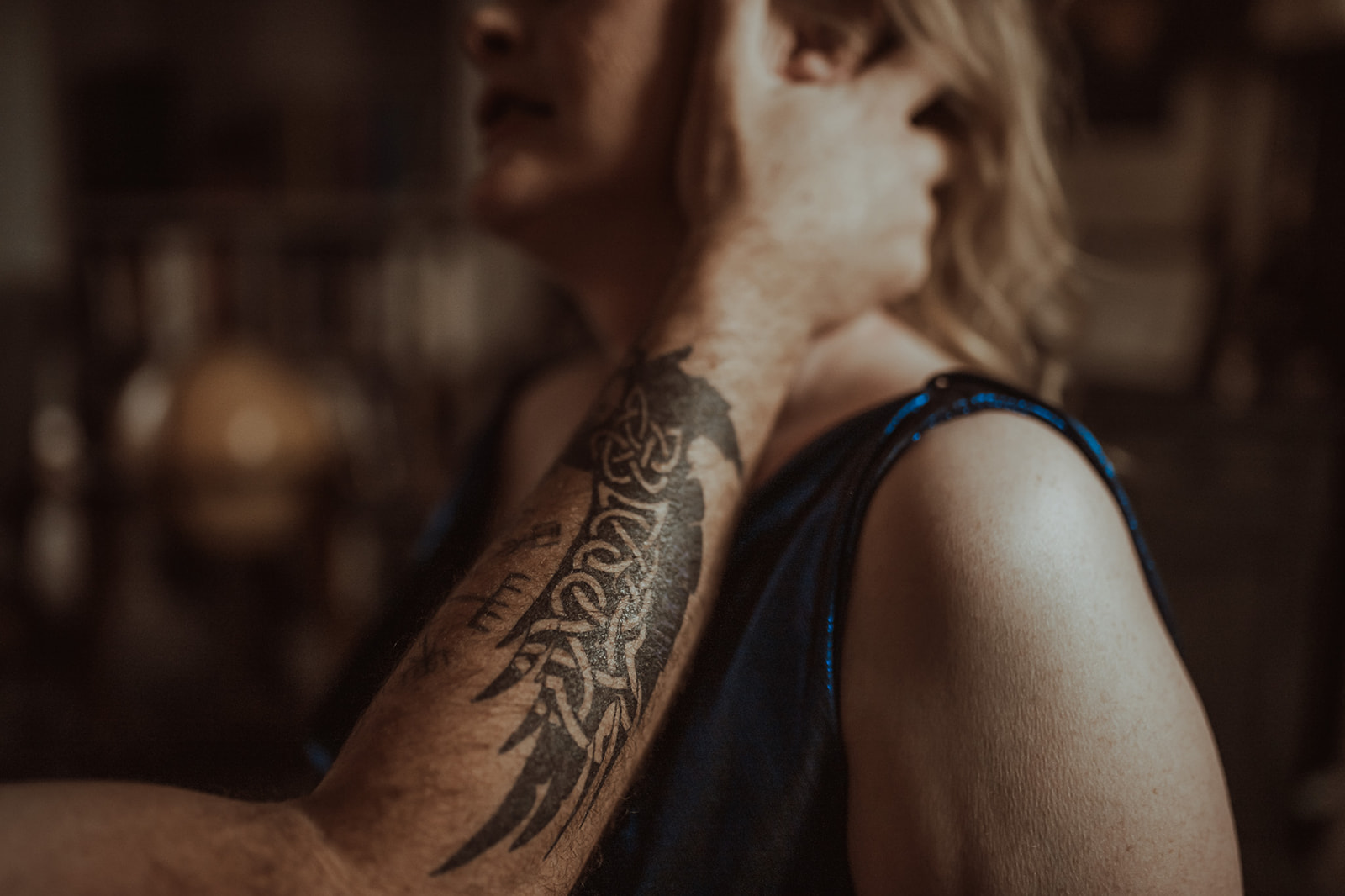 Details of a man's arm as her grasps his wife's neck