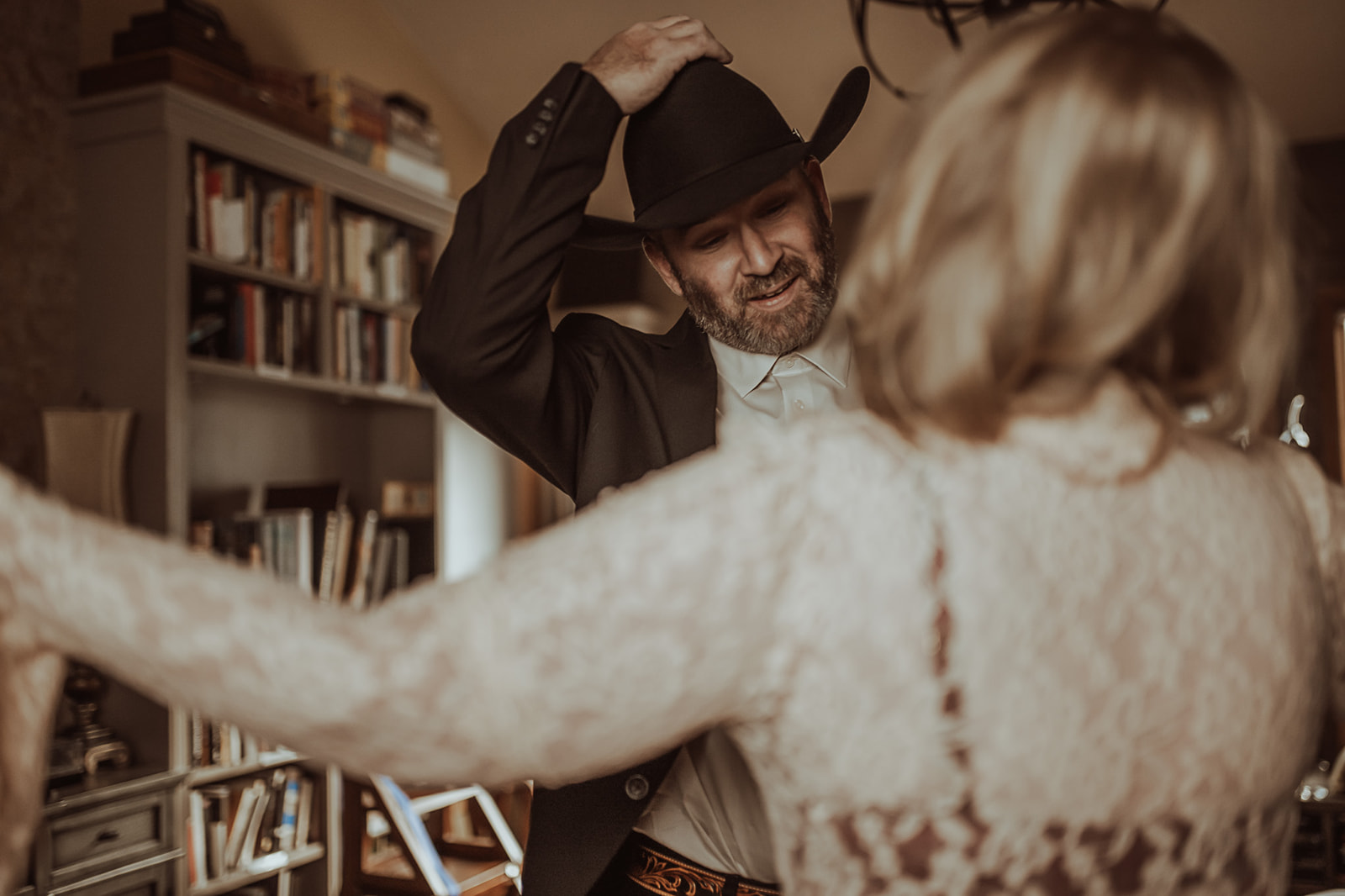 A man removes his cowboy hat in front of his wife indoors after meeting Missoula marriage counselors