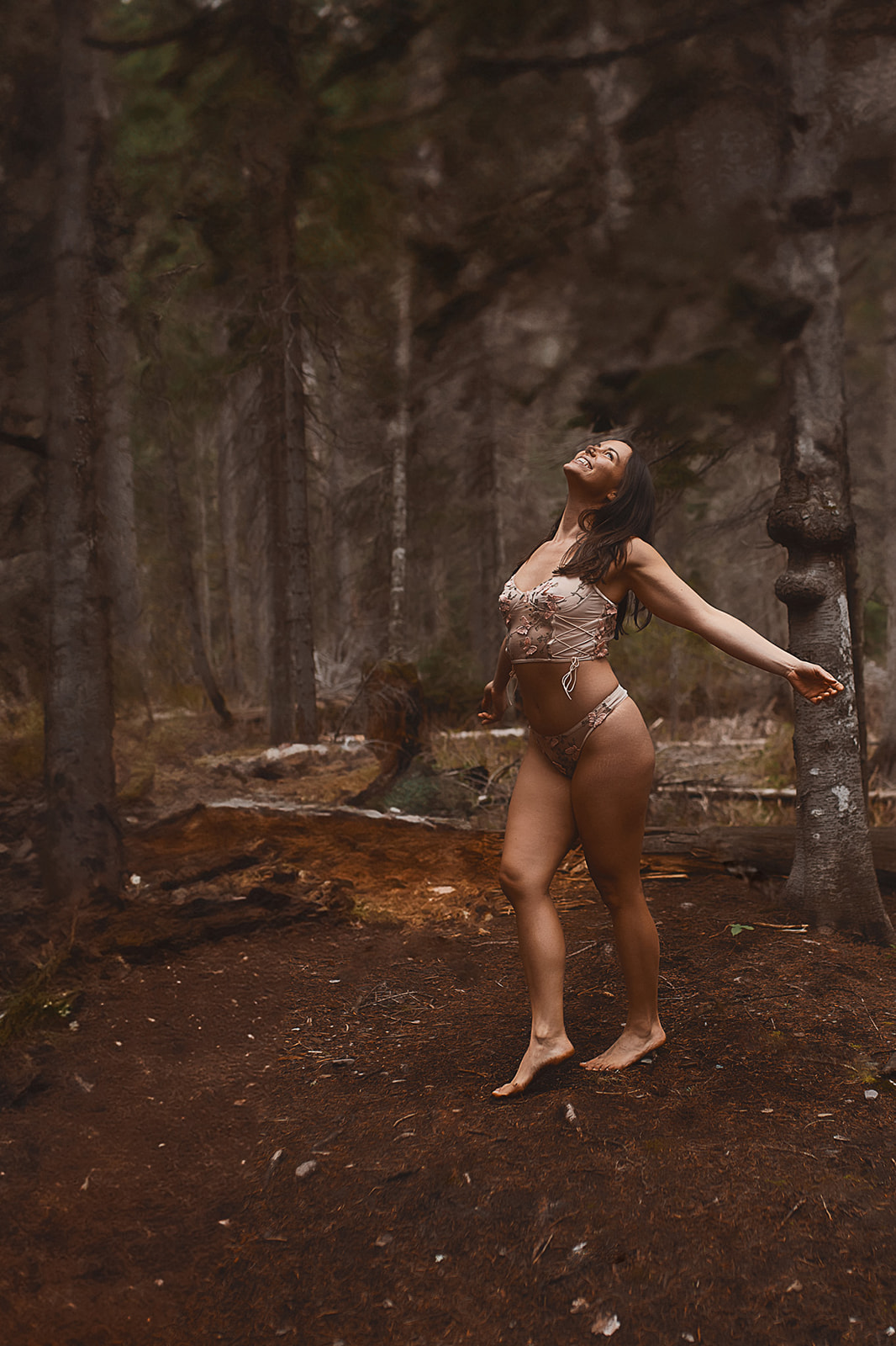 A happy woman dances in a forest in lingerie after visiting Missoula personal trainers