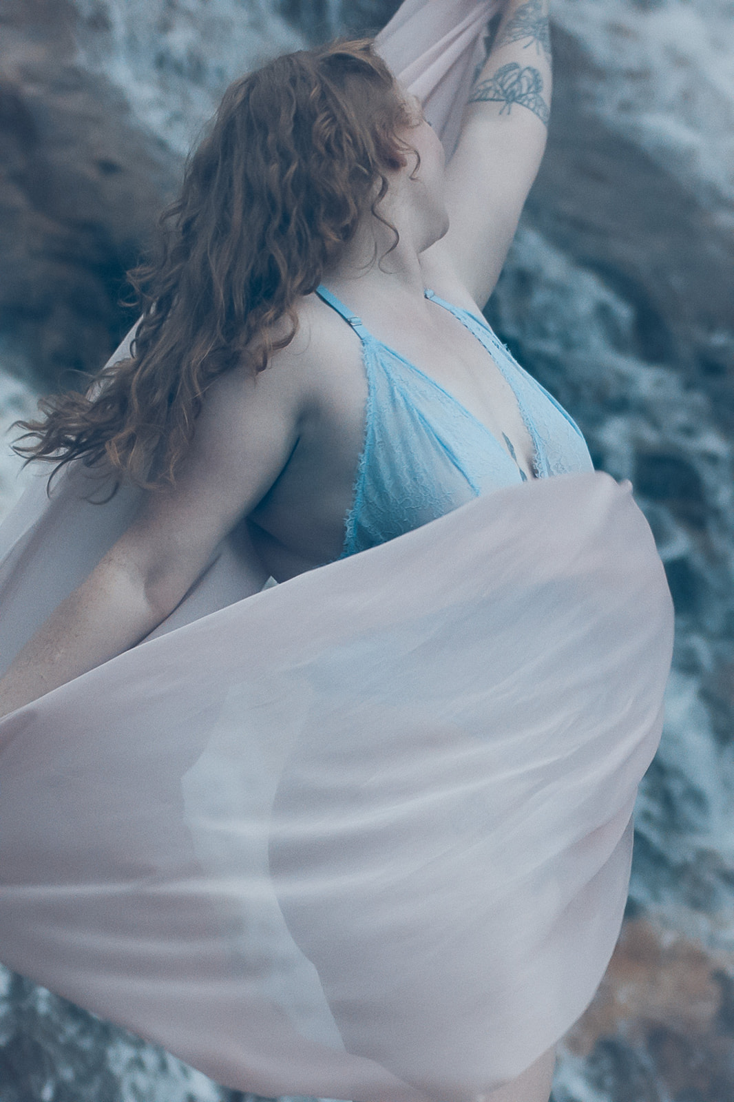 A happy woman in blue lingerie dances with a pink coverup in the forest by a waterfall after some Missoula Yoga
