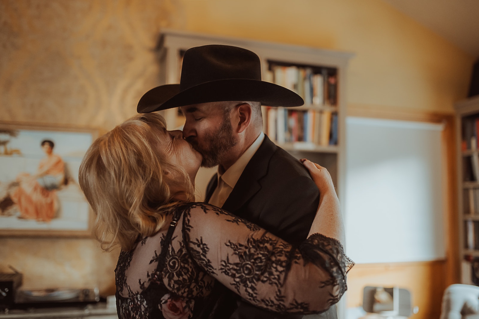 A happy couple in black and cowboy hat embrace for a kiss in a bedroom after enjoying romantic restaurants in Missoula