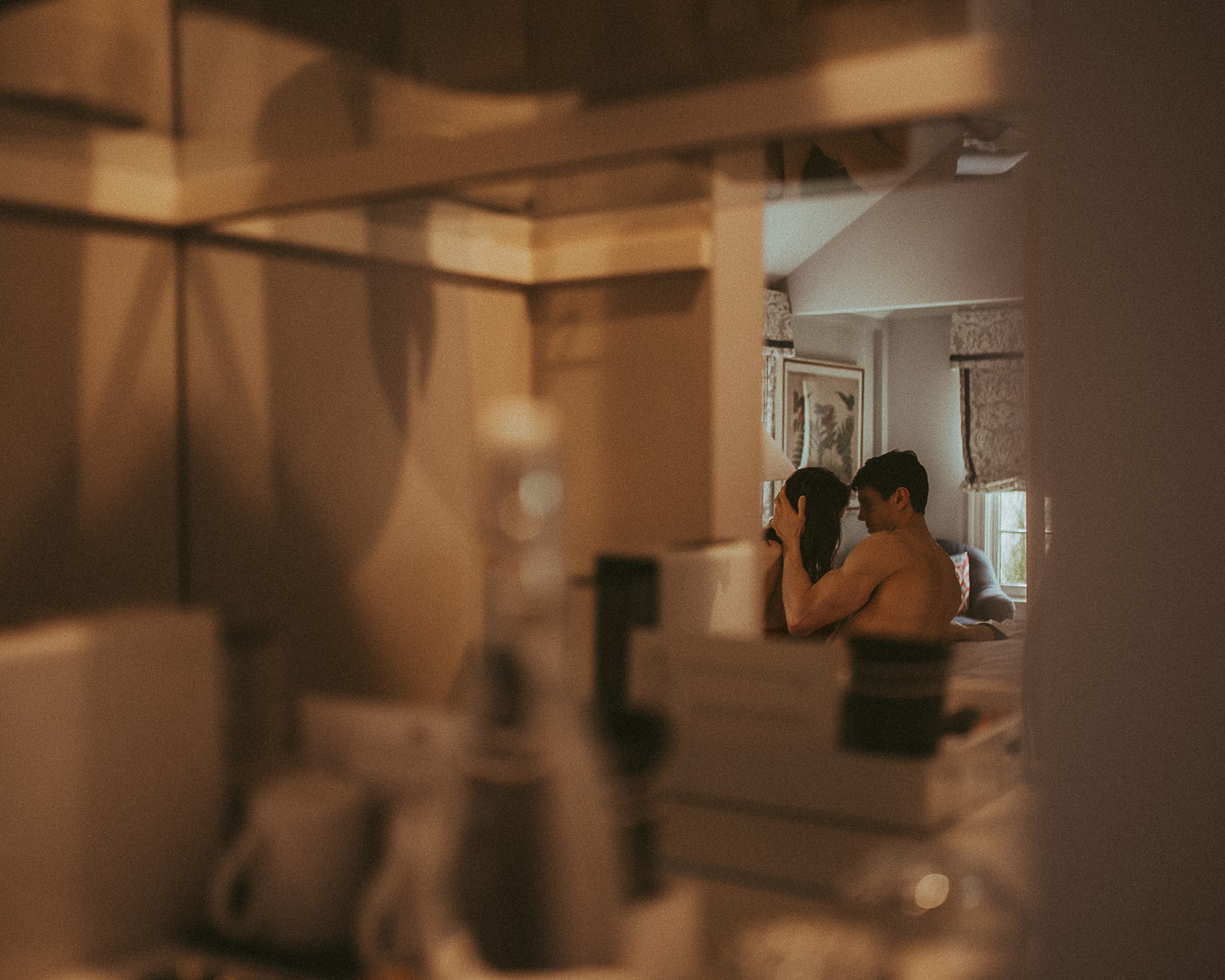 A peak at a couple through a mirror as they get intimate in bed