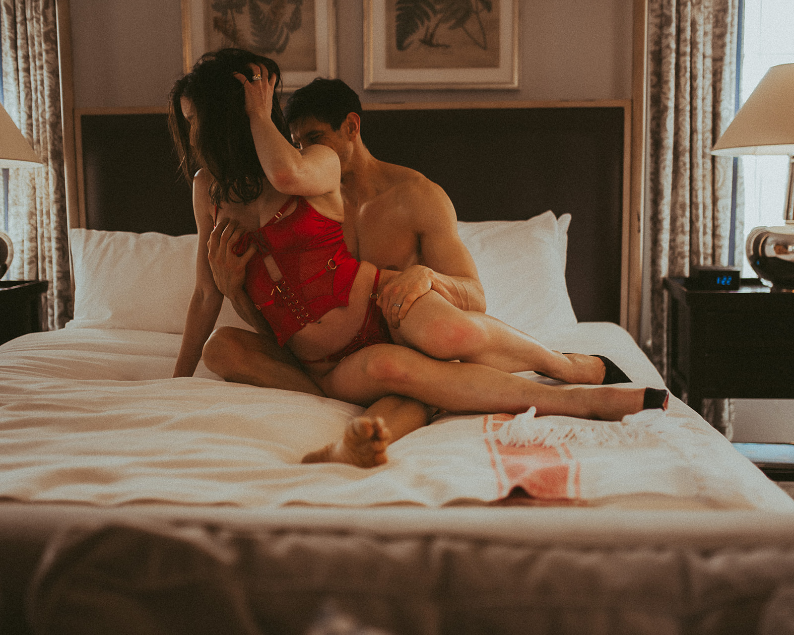 A couple gets intimate in red lingerie on a bed as she sits in his lap after visiting Sex Therapists in Missoula